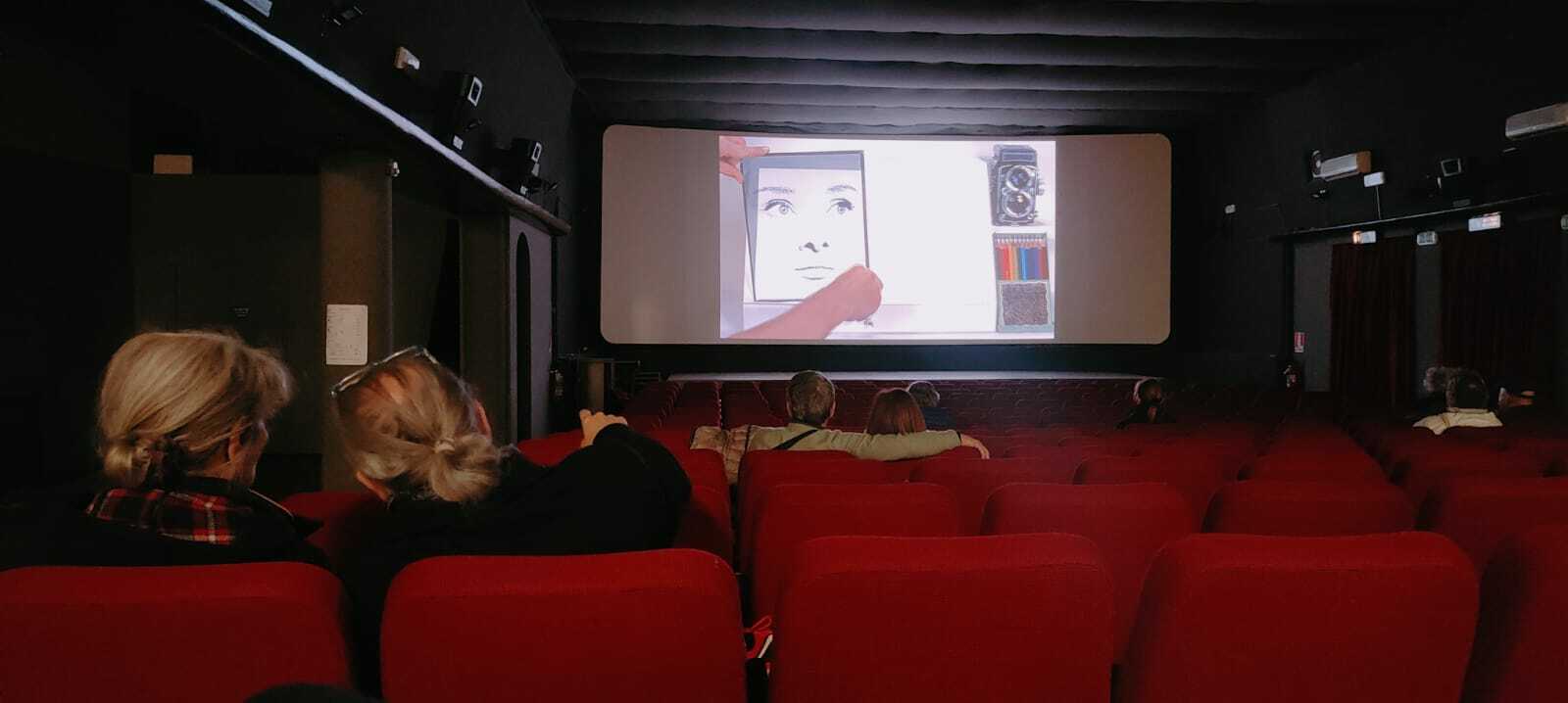 Foto del vecchio Cinema Ariston, nel corso dell'edizione sperimentale di "Un Cinema per Amico" (edizione 2023).<br />
Due coppie anziane sulla scena. Quella in primo piano commenta il film, la seconda si abbraccia mentre guarda la proiezione.