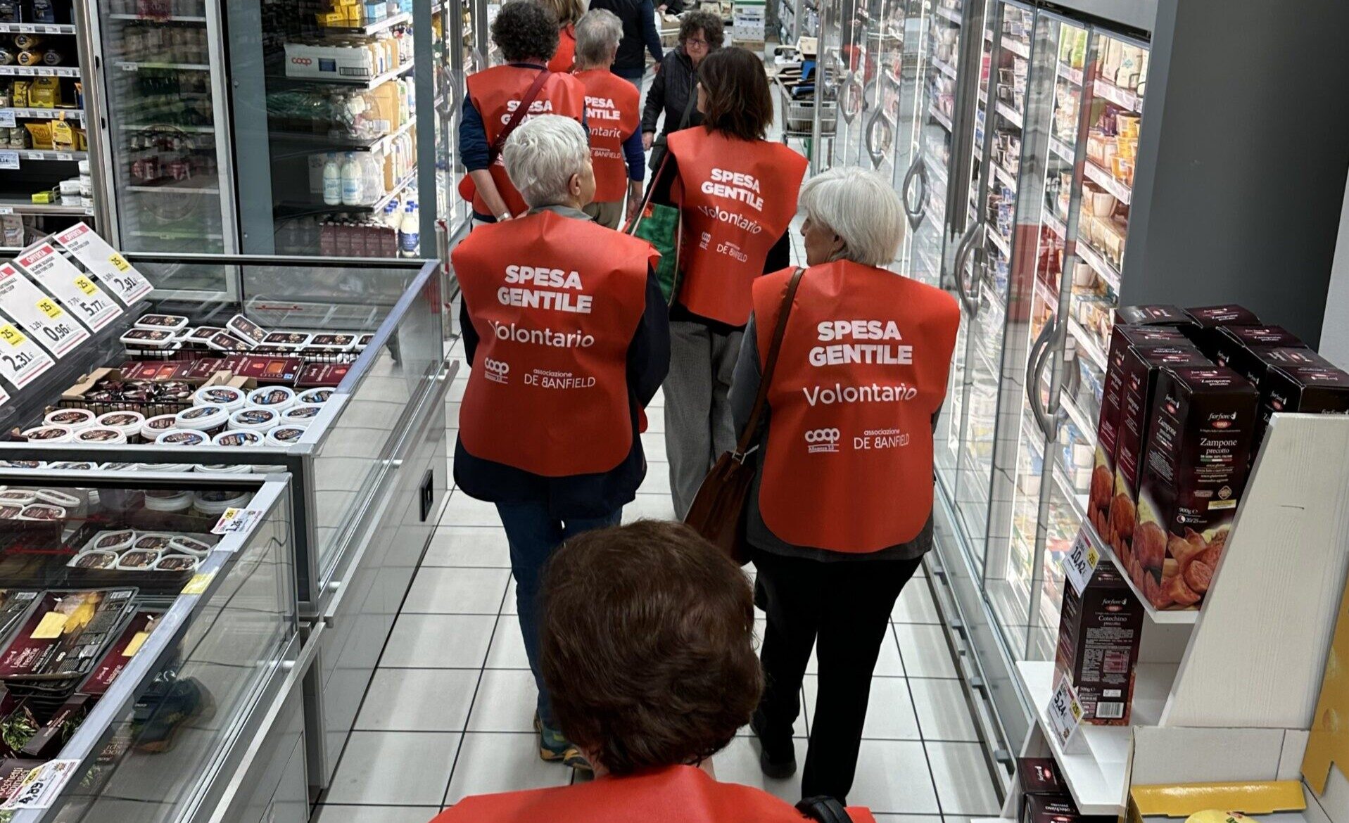 In foto una donna anziana in carrozzina, al tavolo di casa, che porge la mano al cane.