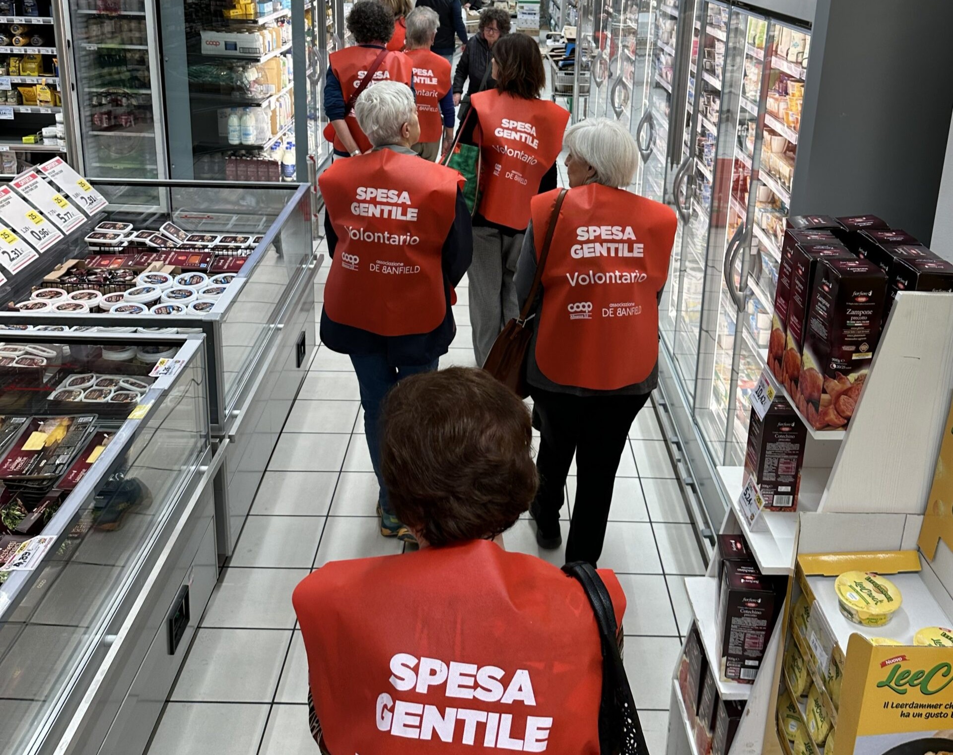In foto una donna anziana in carrozzina, al tavolo di casa, che porge la mano al cane.