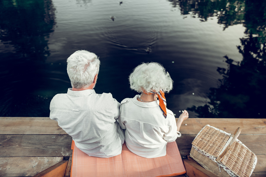 Persone con demenza. Foto di due anziani seduti su un molo.